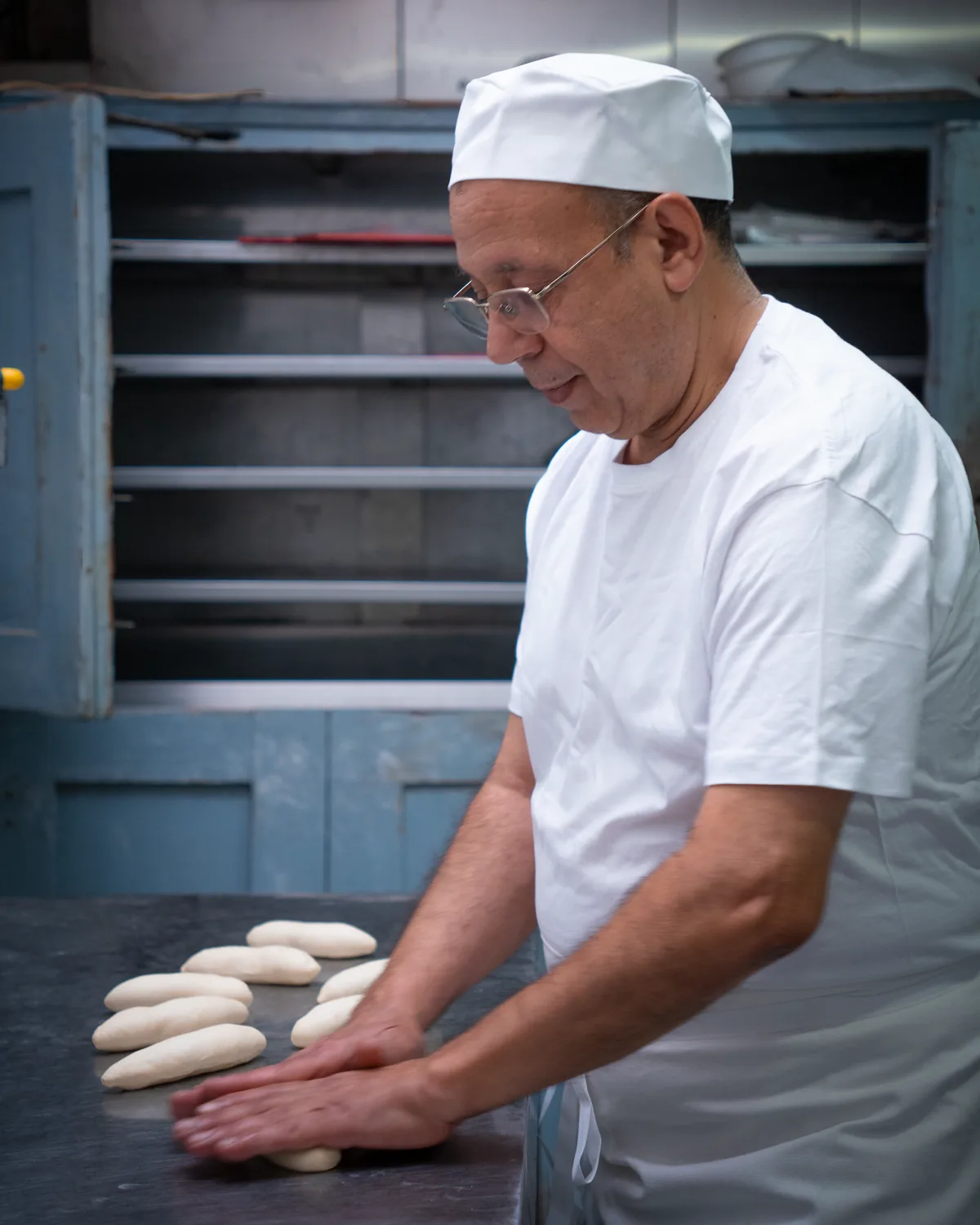 Jamal Ahlaloum façonne à la main des pâtons de pain hot-dog sur le plan de travail