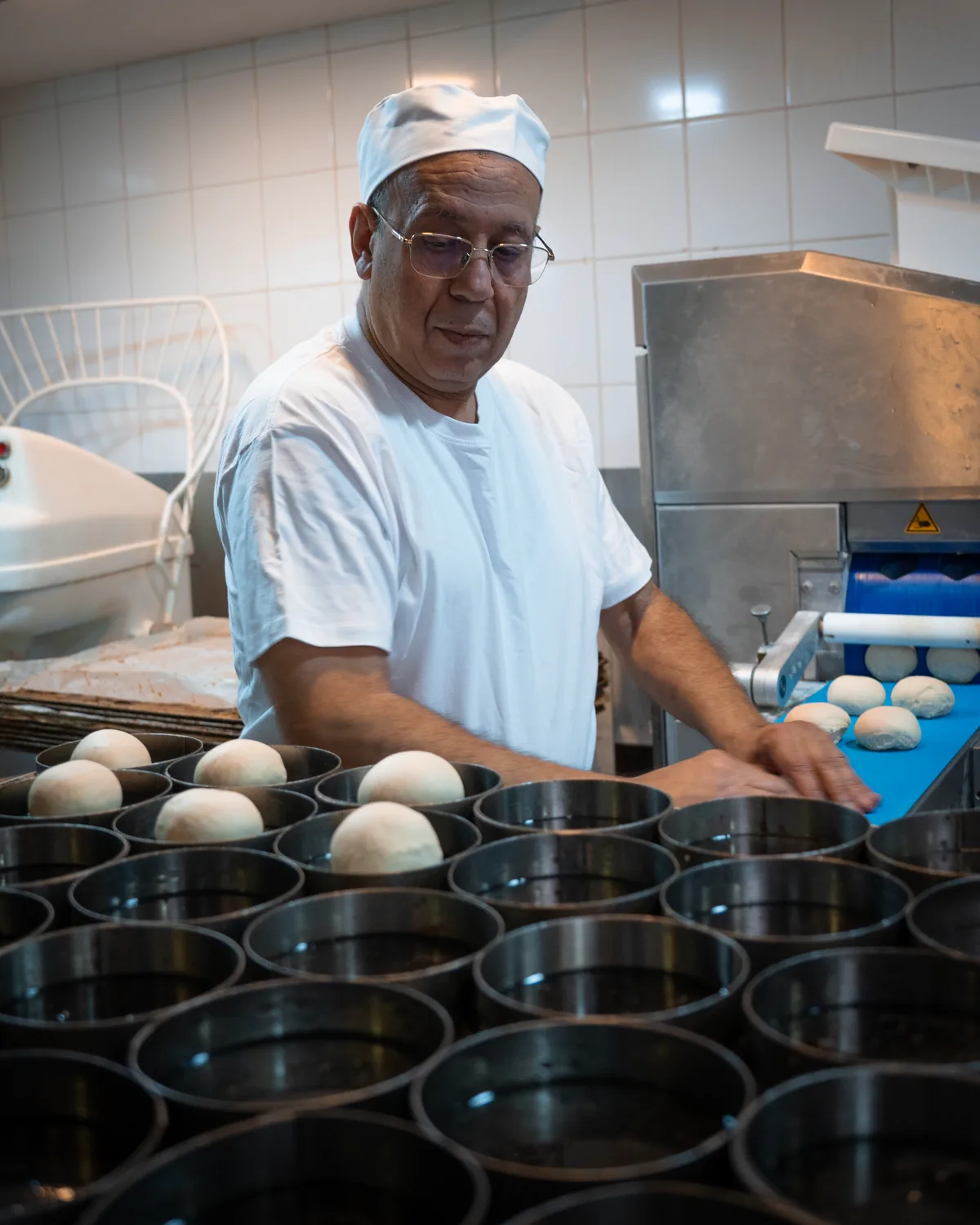 Jamal Ahlaloum dépose les pâtons un à un dans les moules à pain burger