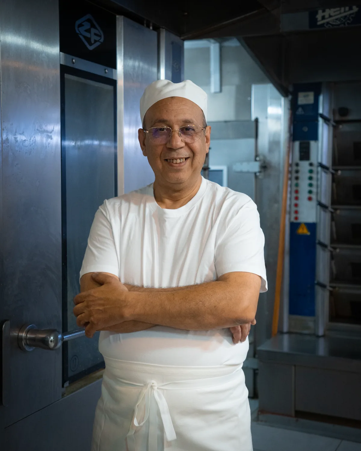 Jamal Ahlaloum, bras croisés, devant le four du fournil
